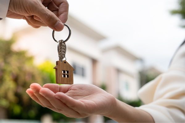En person räcker över en nyckel till ett hus till en annan person