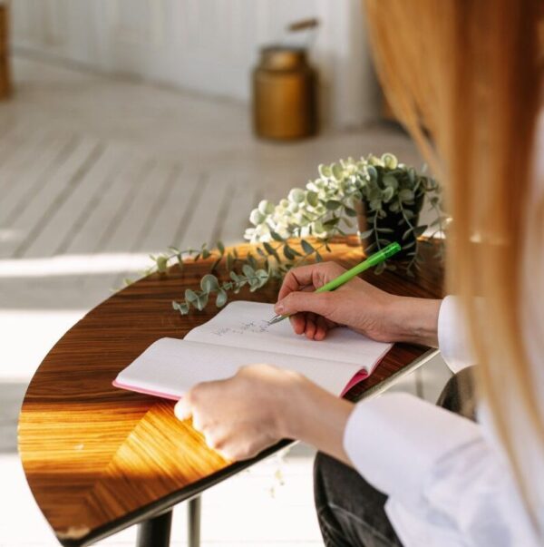 En kvinna sitter vid ett bord och skriver ett gåvobrev