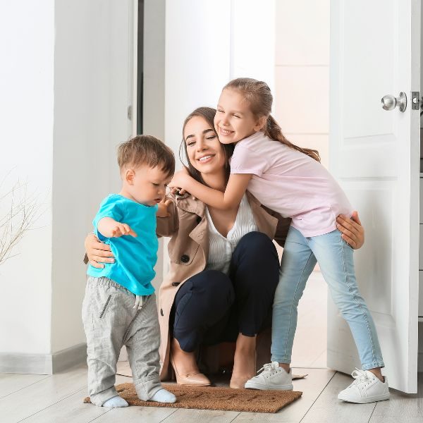 En glad kvinna kramar om två barn