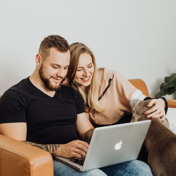 Ett leende par sitter vid datorn och gör en bodelning tillsammans
