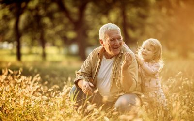 En man med sitt barnbarn på ett fält i kvällsljuset