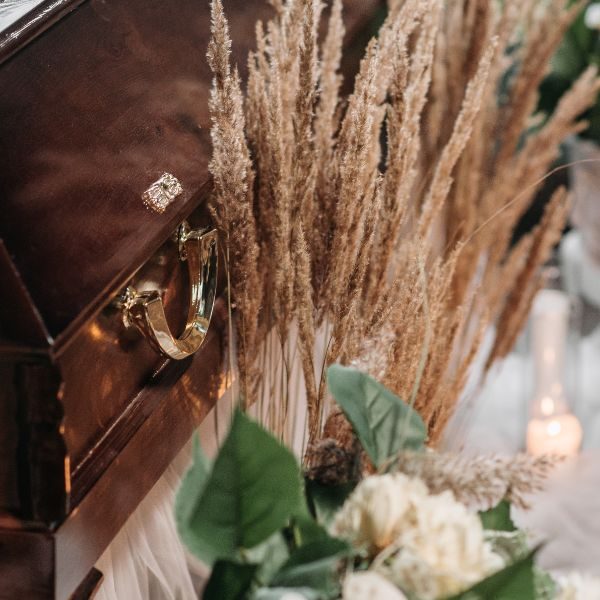 Bild på en kista med blomsterarrangemang bredvid